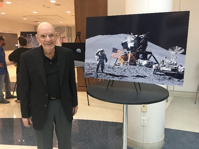 Professor Bill Weppner stands beside a NASA photo of Apollo 11's historic moon landing of the Eagle in 1969