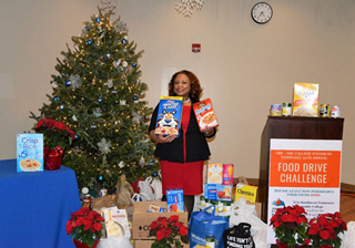 President Tracy D. Hall stands among a field of donated items for the Mid-South Food Bank at the annual holiday open house.