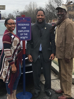SSO President Tilicia Washington (left) and PASO President Ed Ashworth (right) present the Employee of the Month winner Sherman Robinson (center)  his new parking sign