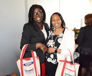 Teaching Academy Director Jennifer Townes and Faculty Support Services Program Specialist Tilicia Washington showcase their new ambassador tote bags filled with marketing materials.