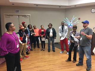 Dr. Jacqueline Taylor (far left) listens to a group present the results of their team-building exercise.