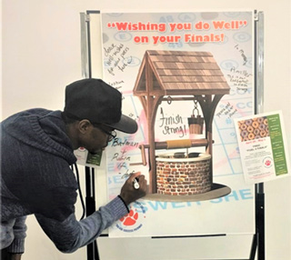 A student at the Whitehaven Center writes an encouraging message to classmates on the interactive Wishing Well during Fuel for Finals.