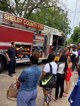 A firefighter with the Shelby County Fire Department explains to a group of youth how a ladder truck is used in emergency situations.