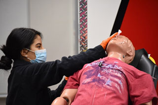 Liliana Mendez sanitizes her patient-mannequin for use by the next EMT student. 