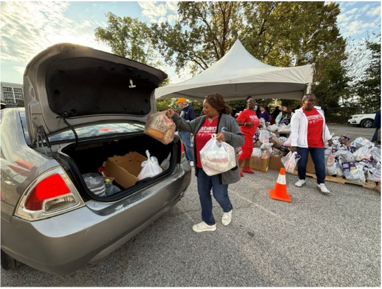 Dr. Hall and some faculty and staff putting groceries in the back of a silver car