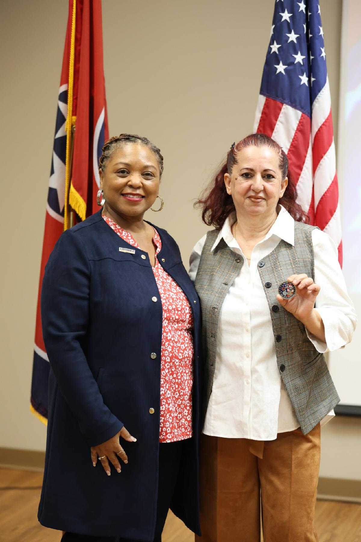 Esma and Dr. Hall standing in front of Tennessee and United States flags